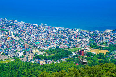 High angle view of townscape by sea against clear blue sky