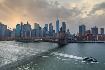 City at waterfront against cloudy sky