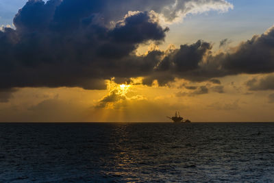 Scenic view of sea against sky during sunset at oil field with oil platgorm on background