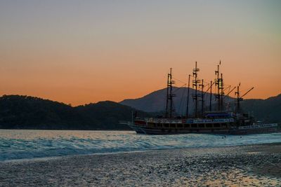 Sailboats in sea against clear sky during sunset