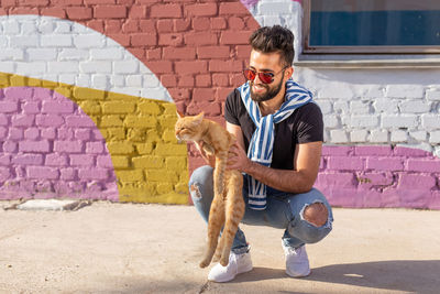 Young man with dog against wall