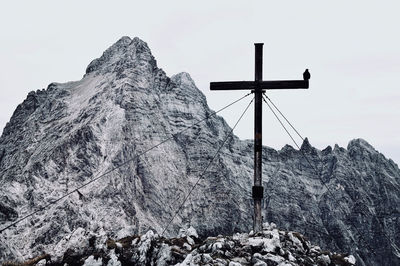 Low angle view of cross on rock against sky