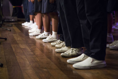 Low section of people standing in row on hardwood floor