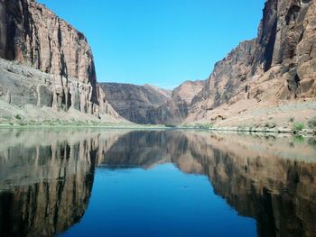 Scenic view of lake by mountains against clear blue sky