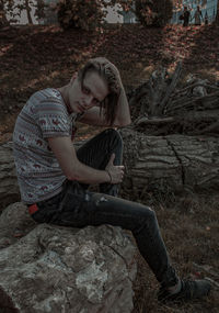 Full length of young woman sitting on rock