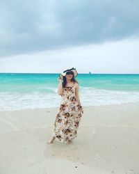 Woman standing at beach against sky