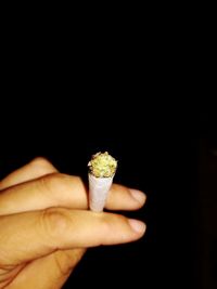 Person holding ice cream cone against black background