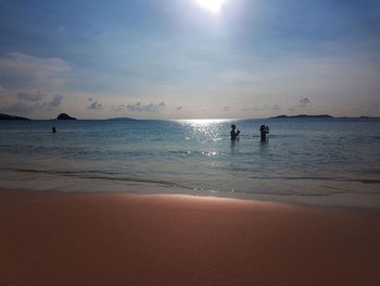 Silhouette people on beach against sky