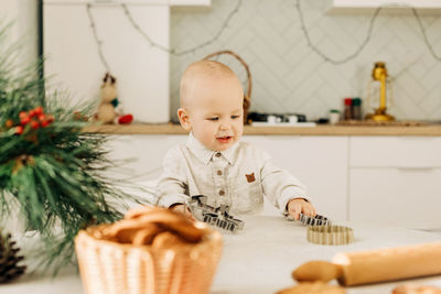 Portrait of a happy boy sitting at a table with cookie cutters. preparation for the holidays