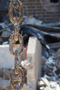 Close-up of rusty chain with demolition in background 