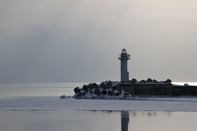 Lighthouse by sea against sky