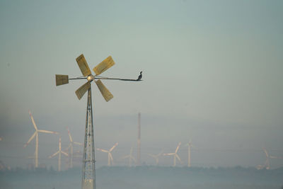 Low angle view of wind turbines on landscape against sky