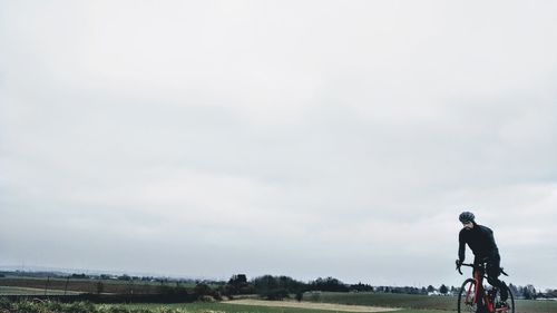 Man riding bicycle on road against sky