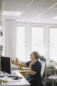 Female nurse doing online consultation using mobile phone sitting at desk in clinic