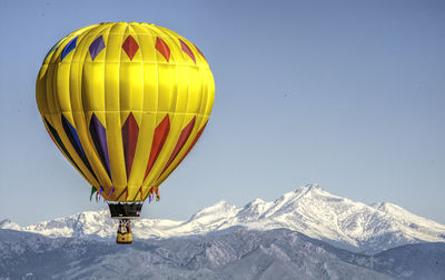 Hot air balloon flying over snowcapped mountain