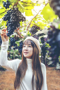 Young woman touching grapes growing at vineyard