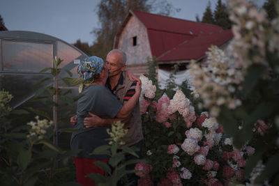 Man and pink flowering plants by building