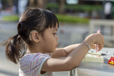 Close-up of cute girl playing with childs play clay at table outdoors