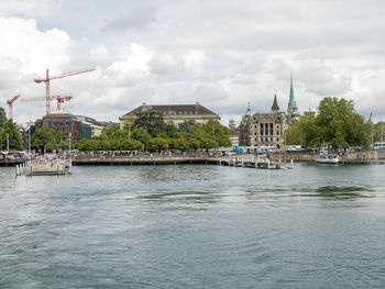 Buildings by river against sky