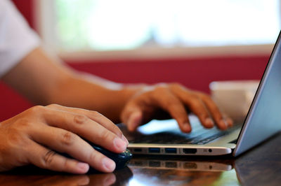 Close-up of man using laptop on table