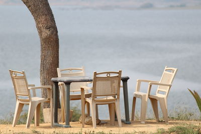 Chairs and tables on beach against sea