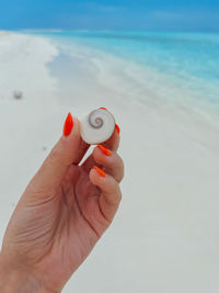 Close-up of hand holding sunglasses on beach