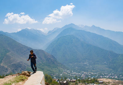 Rear view of man walking on mountain against sky