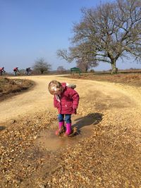 Full length of girl jumping on puddle against clear blue sky