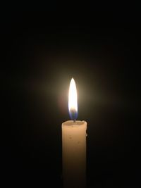 Close-up of lit candle against black background