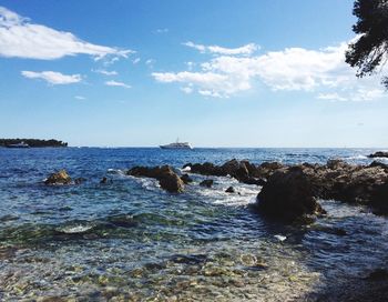 Scenic view of sea and rocks against blue sky