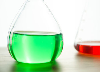 Colorful chemicals in laboratory glassware on table against white background