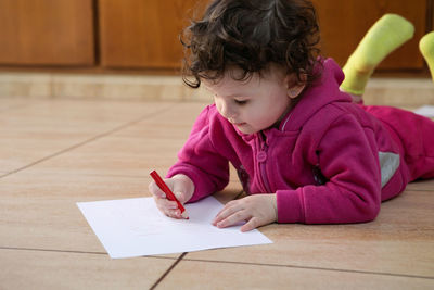 Girl looking away while sitting on table at home