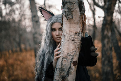 Young woman standing against tree during autumn