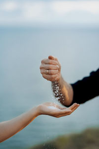 Close-up of hand holding ice over sea