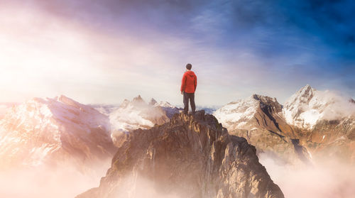 Rear view of man standing on rock against sky