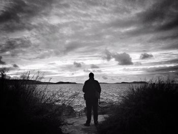 Person standing on field against cloudy sky