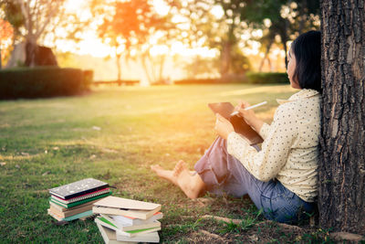 Side view of man reading book on field