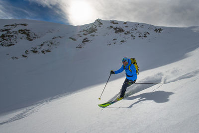 Low angle view of person skiing on snowcapped mountain during winter