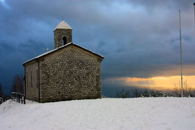 Building on field against sky during winter