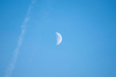 Low angle view of moon against blue sky