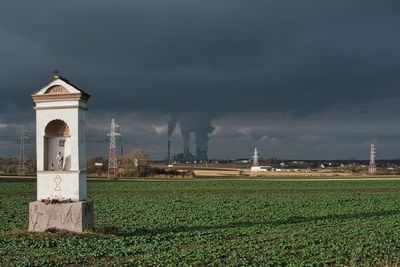 A chapel in a rape field, a coal-fired power plant with chimneys and cooling towers in the distance
