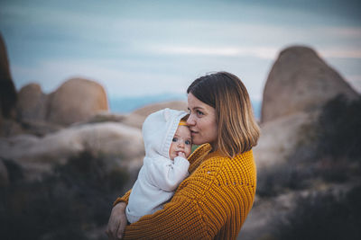 A woman with a baby is standing in a desert of california
