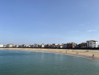 Buildings by sea against blue sky