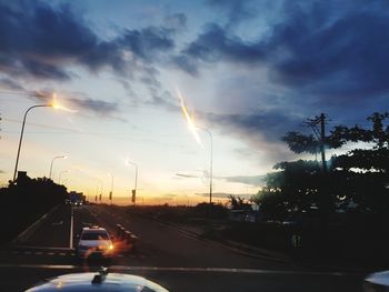 Cars on road against sky during sunset