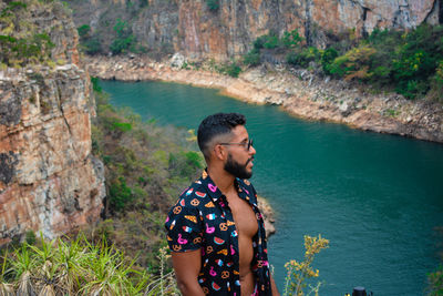 Young man looking at rock formation in water