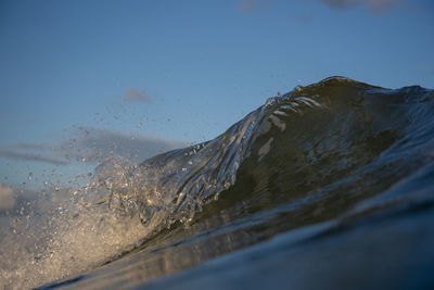 Close-up of water splashing in sea against clear blue sky