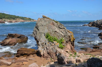 Rock formation on beach against sky