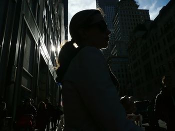 People amidst buildings in city on sunny day