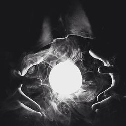 Digital composite image of hand holding illuminated light
