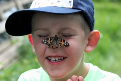 Portrait of smiling young boy with butterfly on the face